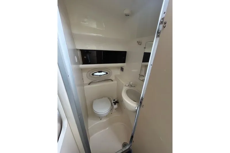 Slide: The Image of 2003 Bayliner 285 boat bathroom with toilet, sink, and porthole window. - 23