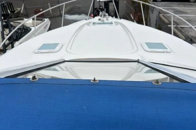 Slide: The Image of 2003 Bayliner 285 boat deck with blue cover, docked in marina. - 8