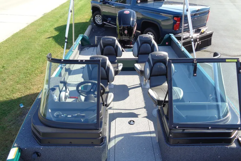 Slide: The Image of 2026 Lund 1800 Explorer Sport boat with seating and windshield, parked near a truck. - 11