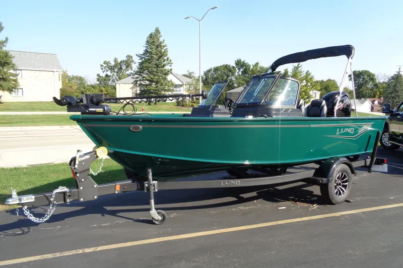 Slide: The Image of 2026 Lund 1800 Explorer Sport boat on trailer, parked outdoors in a sunny setting. - 2