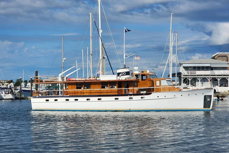 The Image of 1947 Trumpy Raised Pilothouse yacht docked in a marina under a partly cloudy sky. - 0