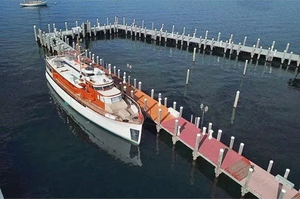 Slide: The Image of 1947 Trumpy Raised Pilothouse yacht docked at a marina with colorful pier. - 2