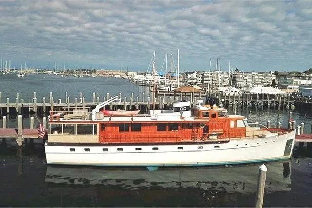 Slide: The Image of 1947 Trumpy Raised Pilothouse yacht docked at a marina under a cloudy sky. - 3