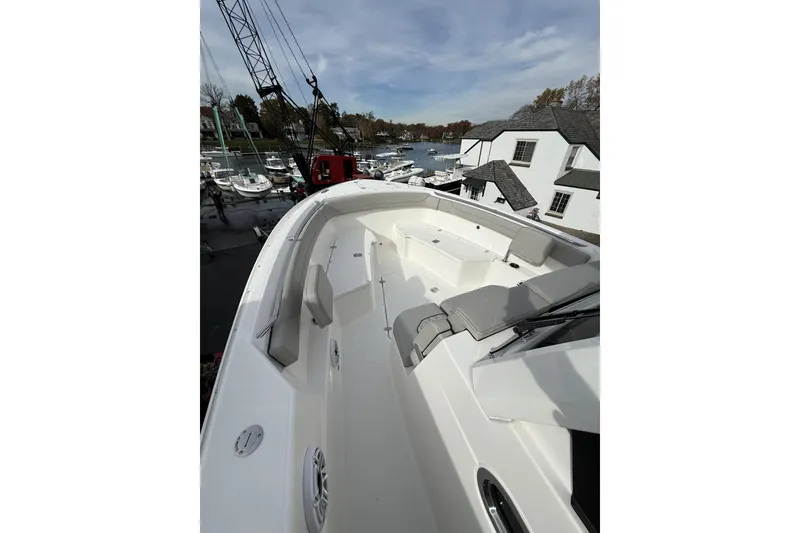Slide: The Image of 2026 Pursuit S 288 Sport boat with spacious deck and seating, docked near waterfront homes. - 9