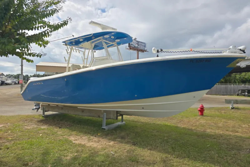 The Image of 2017 Cobia 296 Center Console boat in blue, displayed outdoors on a grassy area. - 1