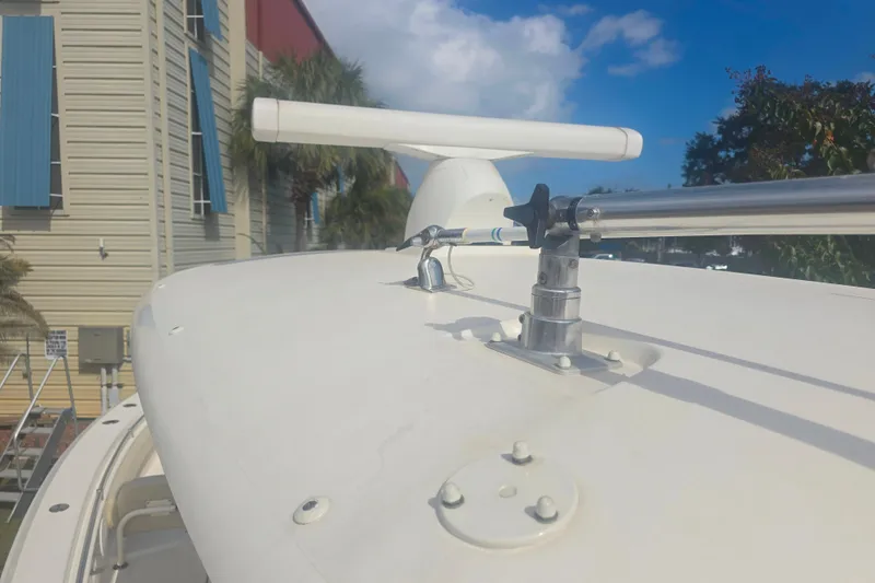 Slide: The Image of 2017 Cobia 296 Center Console boat with radar and railings, docked near a building. - 11