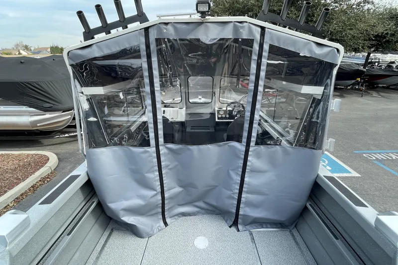 Slide: The Image of 2024 Spartan 185 Astoria boat with protective cover and rod holders in a parking lot. - 10