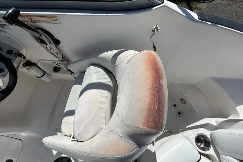 Slide: The Image of 2011 Hurricane SunDeck 2000 OB boat interior with worn captain's seat and control panel. - 16