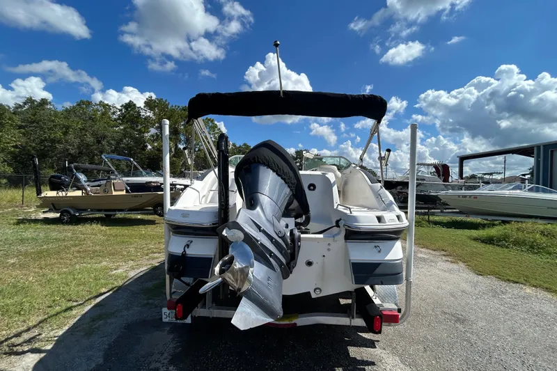 Slide: The Image of 2011 Hurricane SunDeck 2000 OB boat with outboard motor, parked outdoors under blue sky. - 17