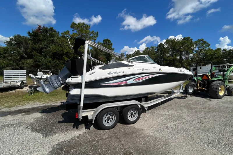 Slide: The Image of 2011 Hurricane SunDeck 2000 OB boat on trailer, parked outdoors under blue sky. - 2