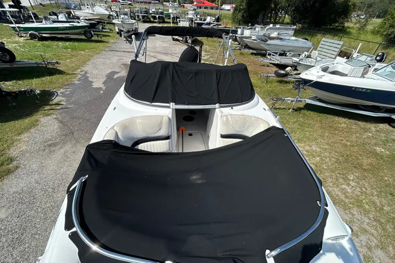 Slide: The Image of 2011 Hurricane SunDeck 2000 OB boat with black covers, parked among other boats. - 3