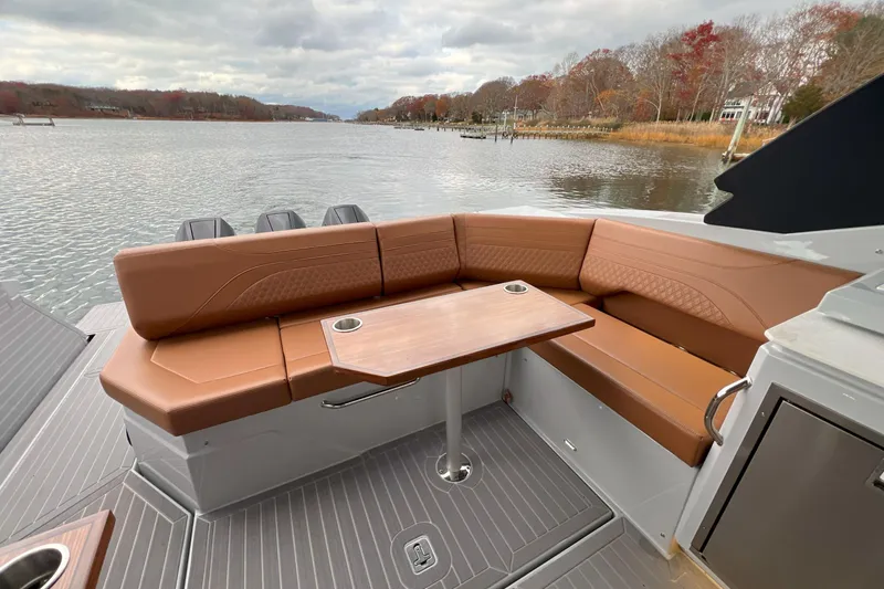 Slide: The Image of 2026 Cruisers Yachts 38 GLS OB with brown seating and table on a serene lake. - 15