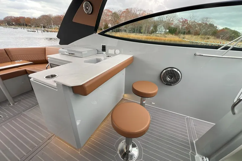 Slide: The Image of 2026 Cruisers Yachts 38 GLS OB interior with seating, bar area, and scenic water view. - 16