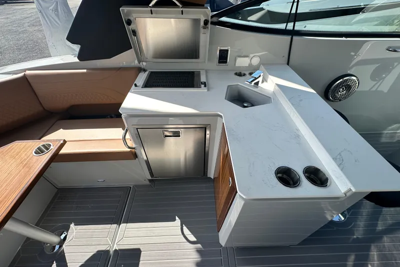 Slide: The Image of 2026 Cruisers Yachts 38 GLS OB boat kitchen with grill, sink, and seating area. - 6