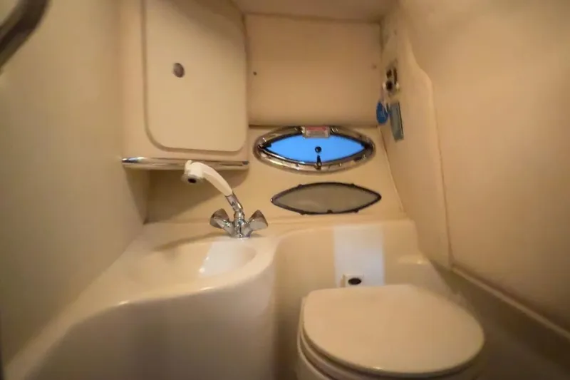 Slide: The Image of 2005 Sea Ray 290 Sun Sport boat bathroom with sink, toilet, and porthole window. - 25