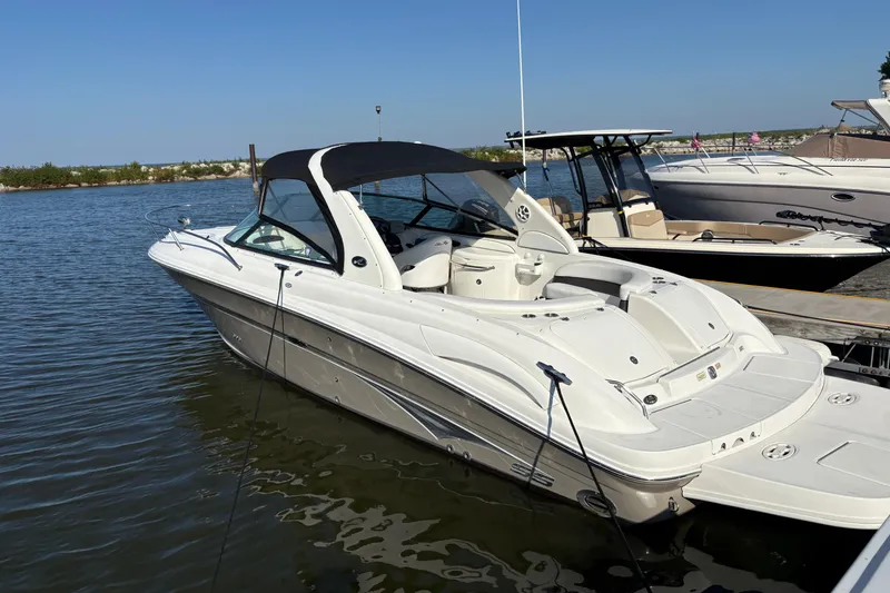 Slide: The Image of 2005 Sea Ray 290 Sun Sport boat docked on calm water under clear blue sky. - 8