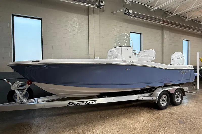 The Image of 2026 Caymas 24 HB boat on a Sport Trail trailer in a showroom. - 0