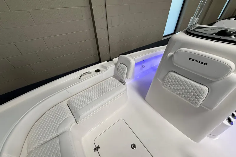 Slide: The Image of 2026 Caymas 24 HB boat interior with white quilted seating and ambient blue lighting. - 15
