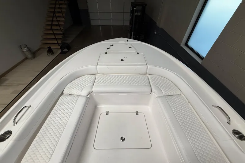 Slide: The Image of 2026 Caymas 24 HB boat interior with white cushioned seating and storage compartments. - 19