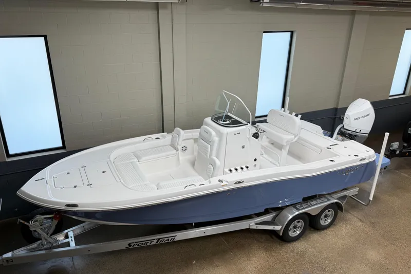 Slide: The Image of 2026 Caymas 24 HB boat on trailer in showroom, featuring sleek design and modern amenities. - 7
