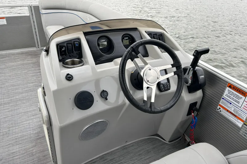 Slide: The Image of 2022 Bennington 22 SS boat dashboard with steering wheel and controls on water. - 9