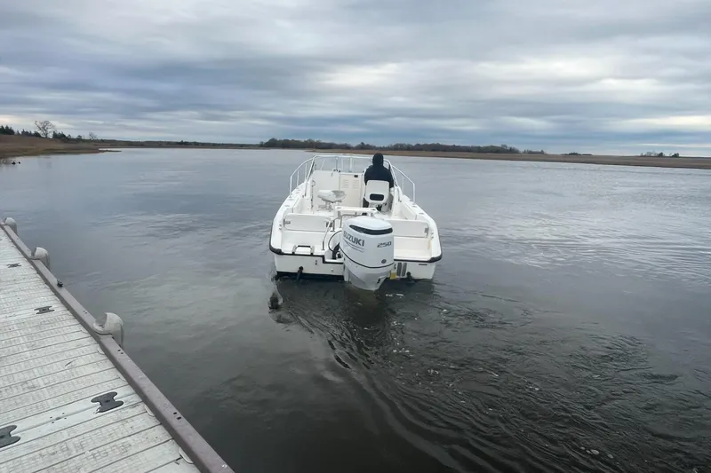 Slide: The Image of 2000 Boston Whaler 21 Conquest boat on calm water near dock, overcast sky. - 3