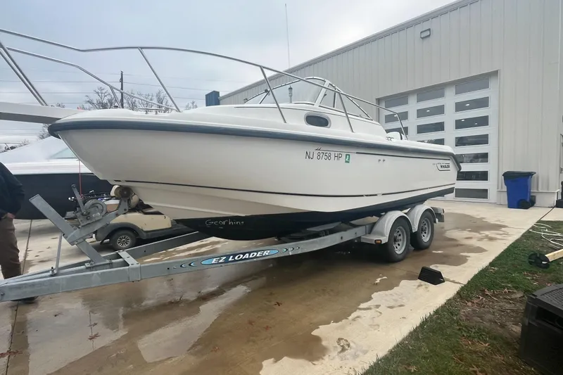 Slide: The Image of 2000 Boston Whaler 21 Conquest boat on trailer outside a garage. - 5