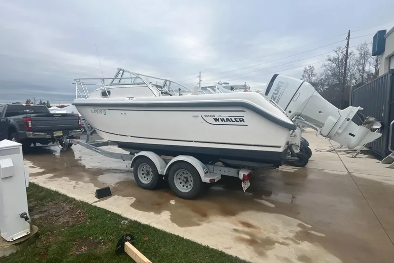 Slide: The Image of 2000 Boston Whaler 21 Conquest boat on trailer, parked outdoors near a truck. - 6