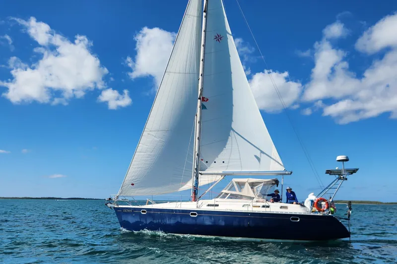 The Image of 1998 Jeanneau Sun Odyssey 42 Center Cockpit sailing on open water under blue skies. - 0