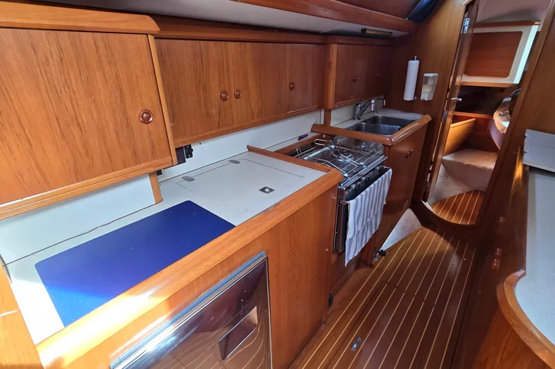 Slide: The Image of Interior of 1998 Jeanneau Sun Odyssey 42 Center Cockpit yacht, featuring a compact wooden kitchen. - 29