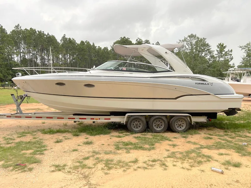 Slide: The Image of 2008 Formula 310 Sun Sport boat on trailer, parked outdoors, surrounded by trees. - 1