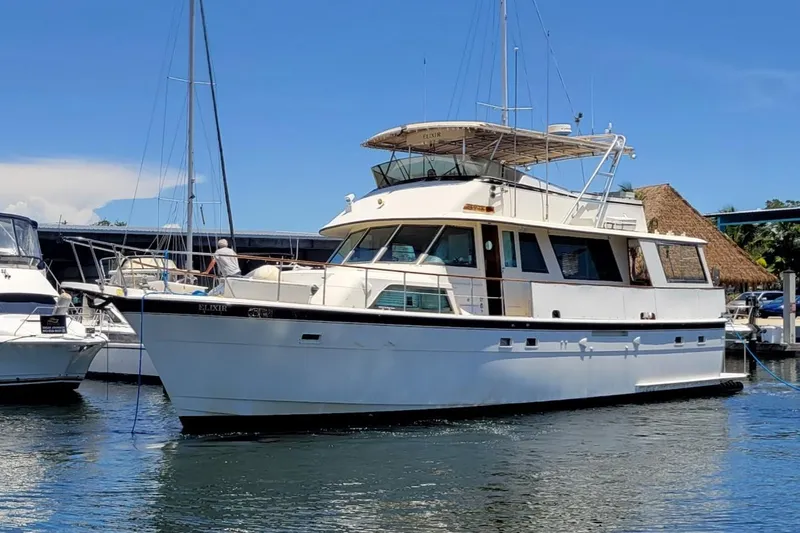 The Image of 1982 Hatteras 56 Wide Body yacht docked in a marina under clear blue skies. - 0