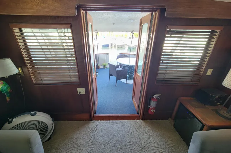 Slide: The Image of Interior view of 1982 Hatteras 56 Wide Body yacht with wooden accents and outdoor seating area. - 12