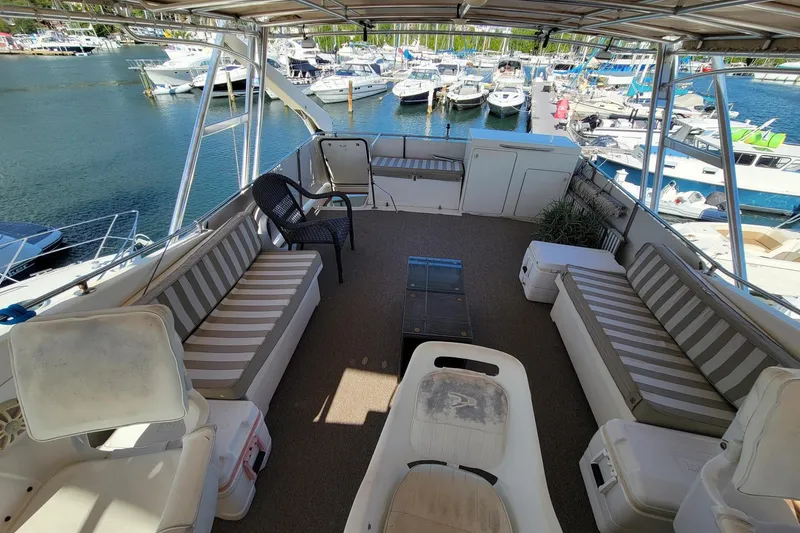 Slide: The Image of 1982 Hatteras 56 Wide Body yacht deck with striped seating, overlooking marina. - 23