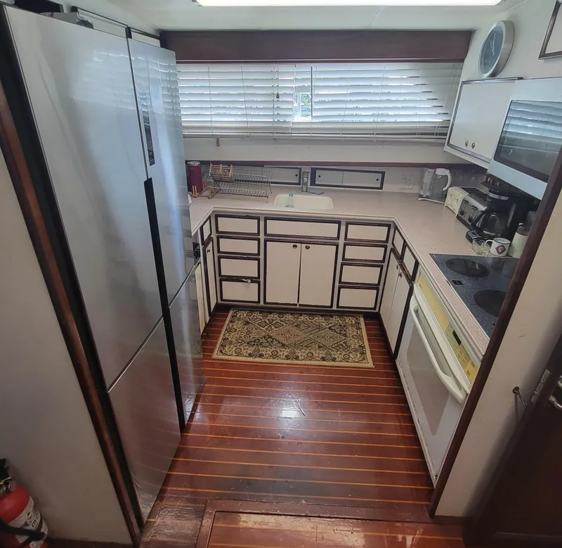Slide: The Image of 1982 Hatteras 56 Wide Body yacht kitchen with wood flooring and modern appliances. - 28