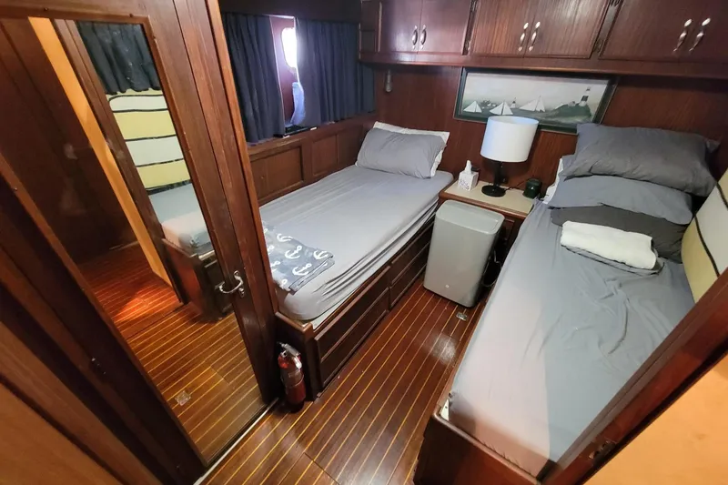 Slide: The Image of 1982 Hatteras 56 Wide Body cabin with twin beds, wooden interior, and nautical decor. - 34