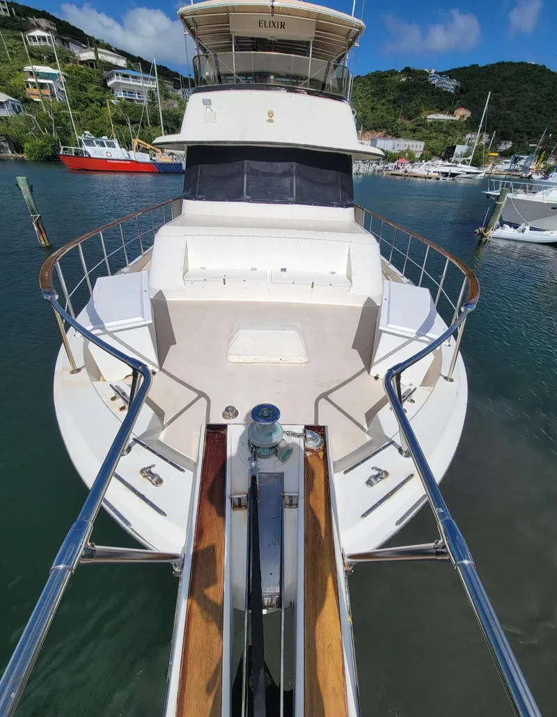 Slide: The Image of 1982 Hatteras 56 Wide Body yacht docked in a scenic marina. - 5