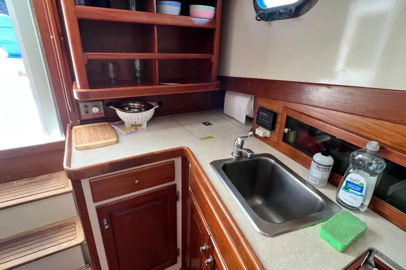 Slide: The Image of 1988 Jarvis Newman Hardtop Cruiser kitchen with sink, wooden cabinets, and countertop accessories. - 9