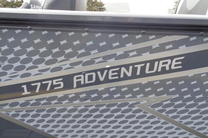 The Image of 2025 Lund 1775 Adventure Sport boat with patterned design and bold lettering. - 0