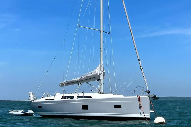 Slide: The Image of 2022 Hanse 388 sailboat anchored on calm blue waters under a clear sky. - 16