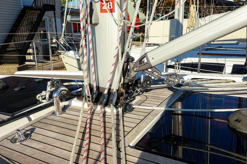 Slide: The Image of 2022 Hanse 388 sailboat deck with rigging and ropes in marina setting. - 17