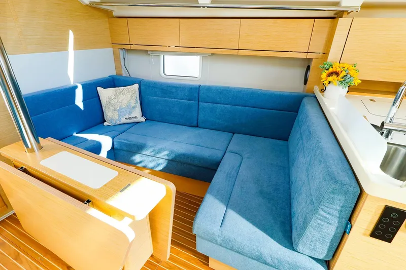 Slide: The Image of Modern 2022 Hanse 388 yacht interior with blue seating, wooden accents, and a bright kitchen area. - 4