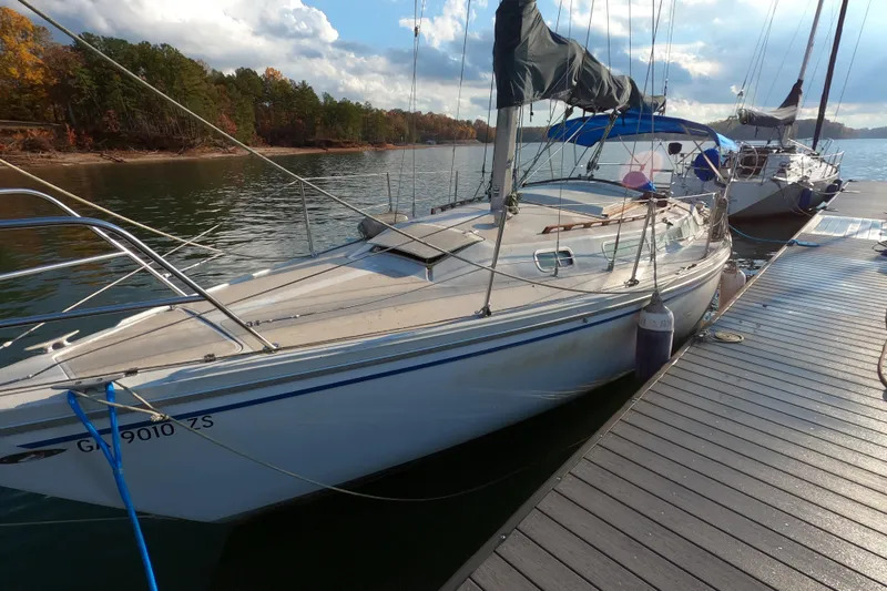 The Image of 1978 Catalina 30 sailboat docked on a serene lake with autumn trees. - 0