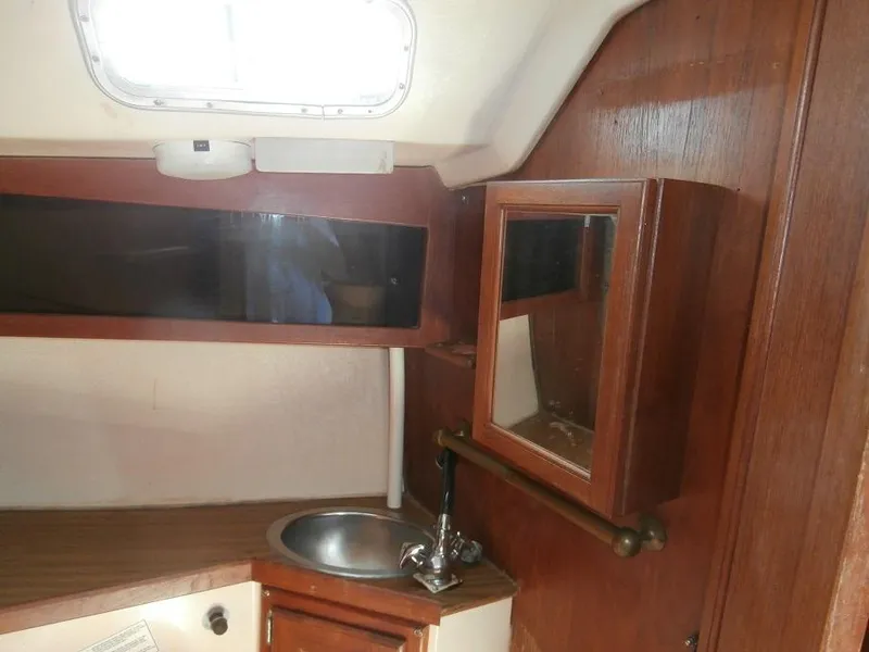 Slide: The Image of 1978 Catalina 30 yacht interior with sink, wooden cabinets, and porthole window. - 10
