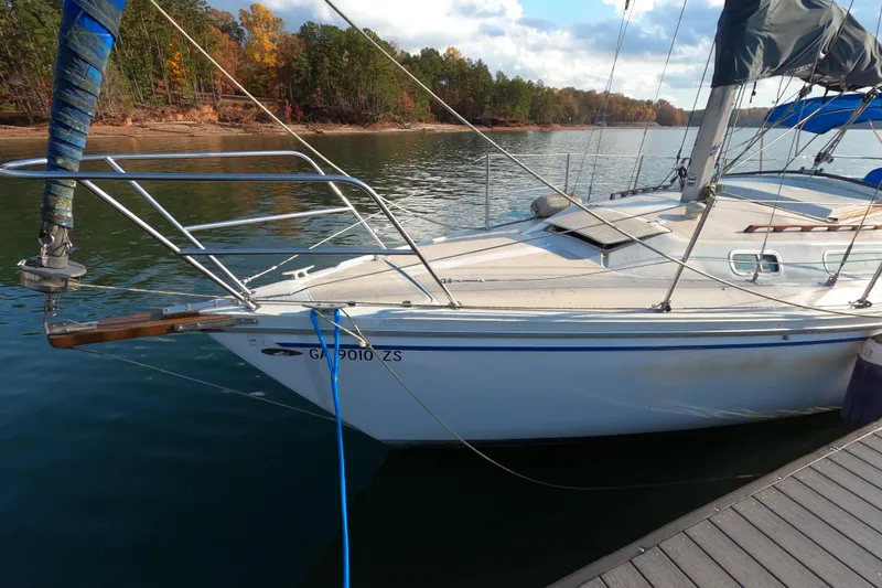 Slide: The Image of 1978 Catalina 30 sailboat docked on a calm lake with autumn trees in the background. - 2