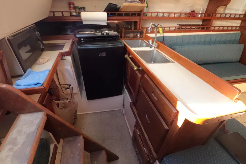 Slide: The Image of 1978 Catalina 30 yacht interior with compact kitchen and seating area. - 20