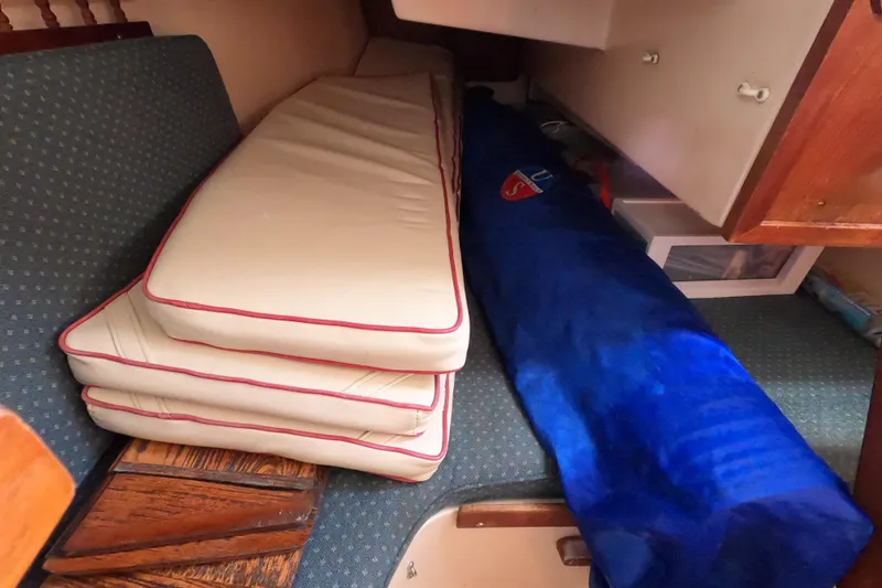 Slide: The Image of Interior of a 1978 Catalina 30 sailboat with stacked cushions and a blue sail bag. - 22