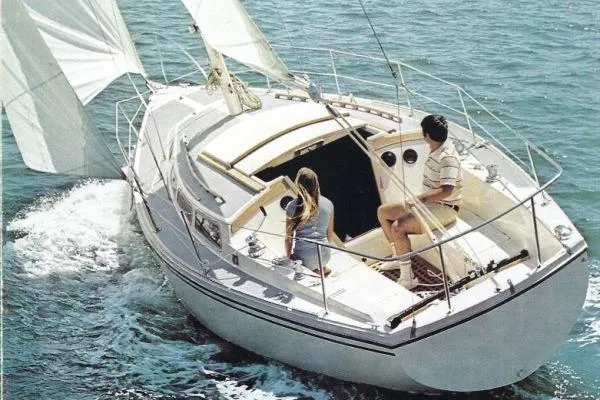 Slide: The Image of 1978 Catalina 30 sailboat cruising on open water with two people onboard. - 30
