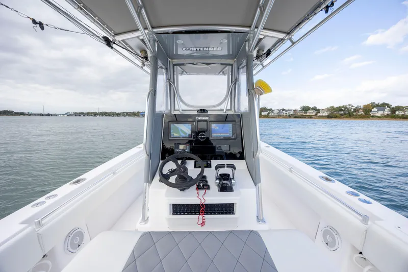 Slide: The Image of 2013 Contender 32 Tournament boat cockpit with steering wheel and navigation screens on calm water. - 19