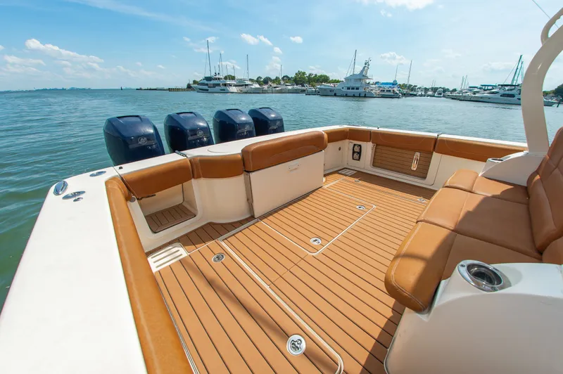 Slide: The Image of 2016 Scout 42LXF: Spacious deck with brown upholstery, four outboard engines, docked in a harbor. - 11